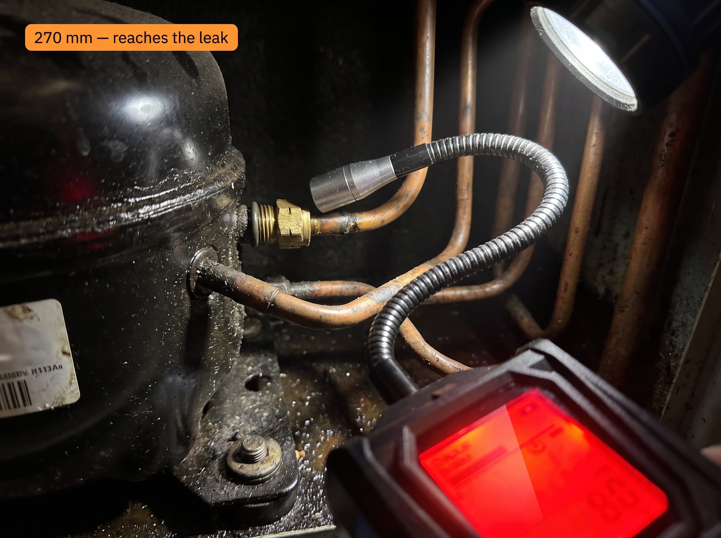 Vavren's 270mm flexible gooseneck probe reaching a fitting behind a compressor, screen glowing red on a hit